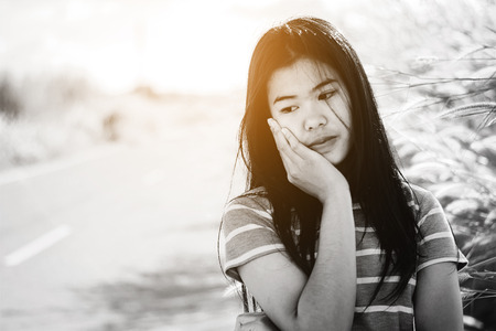 Portrait  beautiful Asian woman in depression and frustration sitting on roadの写真素材