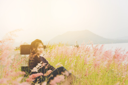 Woman enjoy grass flower in meadow at sunsetの写真素材