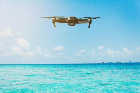 Flying drone above the sea with ship and cloudy sky backgroundの写真素材