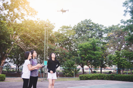 Girls are enjoy playing control flying drone on sky