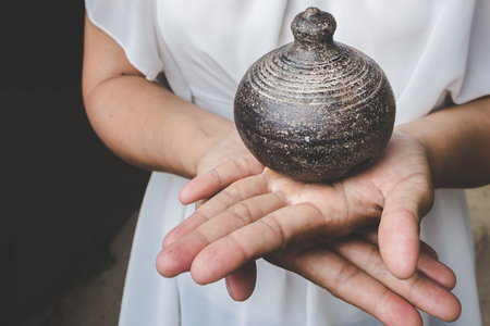 old Thai antique clay pot earth ware on palm of womanの写真素材
