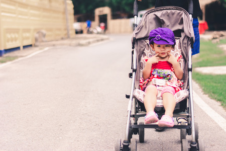 cute Asian baby sitting on baby stroller carriage and posing smilingの写真素材