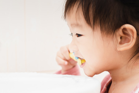 Sweet Asian child little girl brushing her teeth in bathroomの写真素材