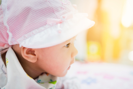 sweet asian baby laying  on bed at home with gradientの写真素材