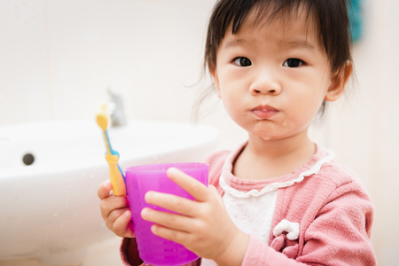 Sweet Asian child little girl brushing her teeth in bathroomの写真素材