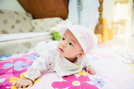 sweet asian baby laying  on bed at home with gradientの写真素材