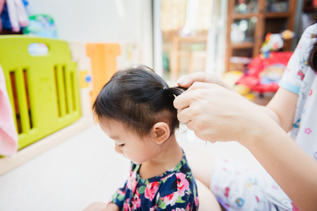 Asian lady weaving braids hair for Child little at homeの写真素材