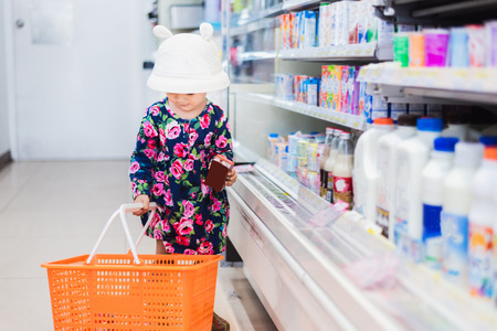 Sweet Asian girl shopping in mini mart with basket, enjoy buying thing in martの写真素材