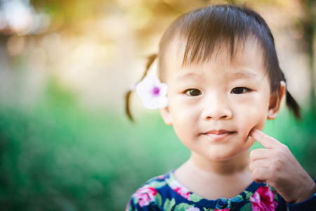 Portrait of Sweet Asian child little girl smiling with flower on her earの写真素材