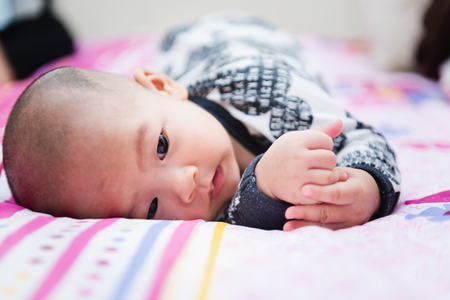 Closeup of happy little child playing over the bed in a relaxed morning with her little baby sister.の写真素材
