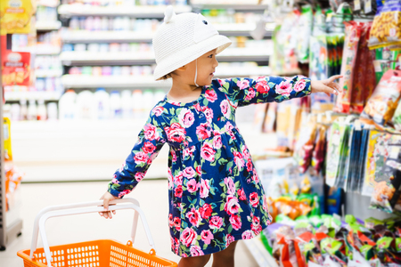 Sweet Asian girl shopping in mini mart with basket, enjoy buying thing in martの写真素材
