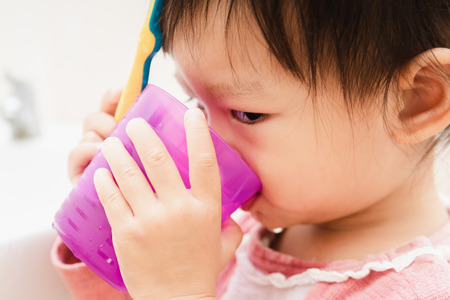 Sweet Asian child little girl brushing her teeth in bathroomの写真素材