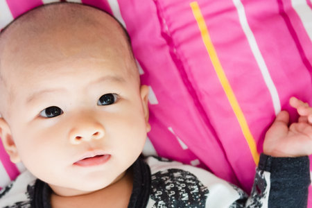 Closeup of happy little child playing over the bed in a relaxed morning with her little baby sister.