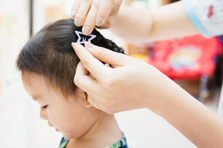 Asian lady weaving braids hair for Child little at homeの写真素材