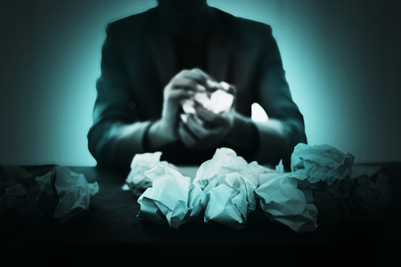 Depress and hopeless man under interrogate with lower head with trash paper on frontの写真素材