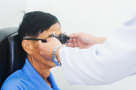 Elderly man having hes eyes examined by an eye doctor on a testing tool in modern clinic, optometry conceptの写真素材