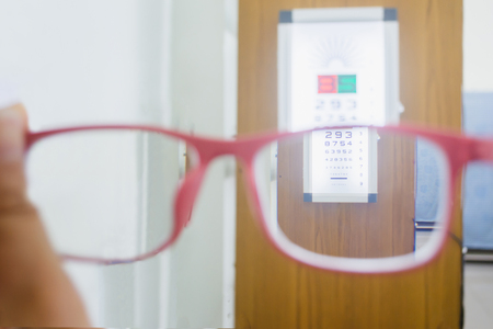 Hand holding glasses with Eye Test Chart ,Vision Exam backgroundの写真素材