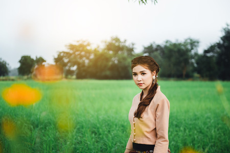 Beautiful Asian woman in local dress standing and enjoy natural on bamboo bridge in rice fieldの写真素材