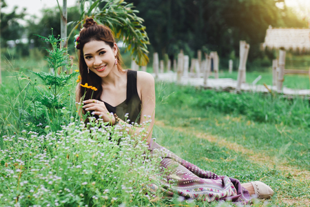 Beautiful Asian woman in local dress sitting on ground and enjoy natural  in rice fieldの写真素材
