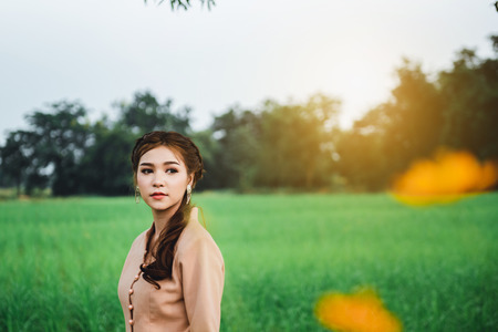 Beautiful Asian woman in local dress standing and enjoy natural on bamboo bridge in rice fieldの写真素材