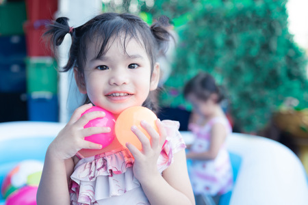 little children enjoy and have fun playing water in inflatable pool with colorful of small ballsの写真素材