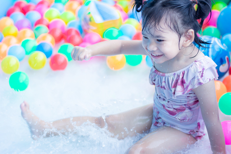 little children enjoy and have fun playing water in inflatable pool with colorful of small ballsの写真素材