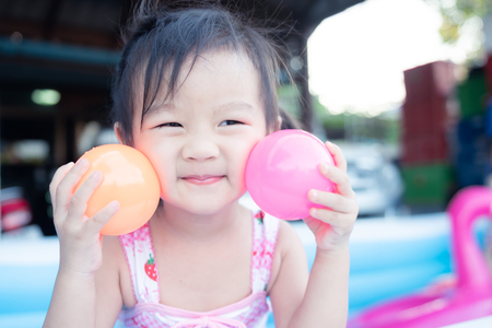 little children enjoy and have fun playing water in inflatable pool with colorful of small ballsの写真素材