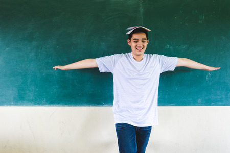 Boy extend the arms with book on head, standing before chalkboard, punishing in the classroomの写真素材