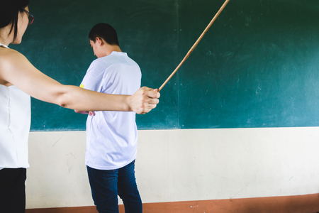 Students being physically punished by teacher with small wooden stickの写真素材
