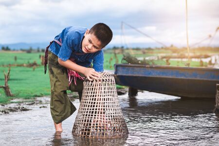 Children catching fish and have fun in the canal. Life style of children in countryside of Thailand.の写真素材