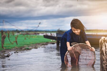 Children catching fish and have fun in the canal. Life style of children in countryside of Thailand.の写真素材