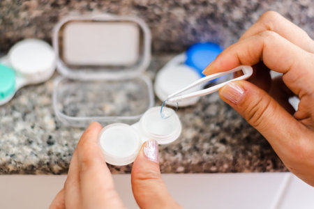 Accessories for working with contact lenses. Tweezers with contact lens and plastic container on...