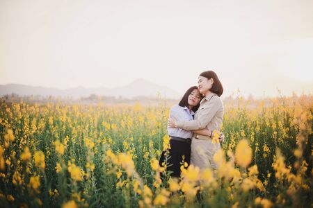 Young Asian Teacher with students  walking through Crotalaria flower field and enjoy at sunsetの写真素材