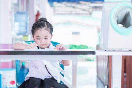 A Cute and lovely Asian baby girl in nurse uniform dress writing a reportの写真素材