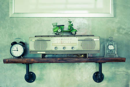 Retro broadcast radio receiver on wooden shelf with concrete wall background.の写真素材