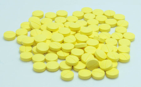 yellow medications tablets in a beaker