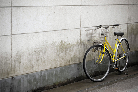 Parked Japan yellow bicycle with the white dirty wall.の写真素材
