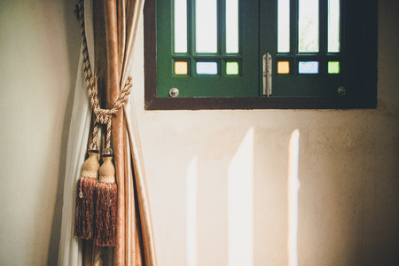 Curtain is tied with classic style tassels beside the vintage window.の写真素材