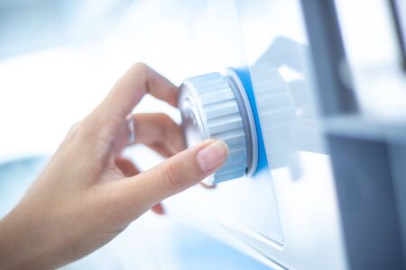 Close up hand is turning dial knob of laundry washing machine.の写真素材