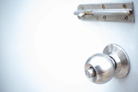 Stainless stell door knob with door lock on the white door.
