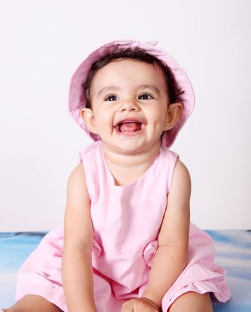 Beautiful baby looking up, Smiling and with pink hatの写真素材