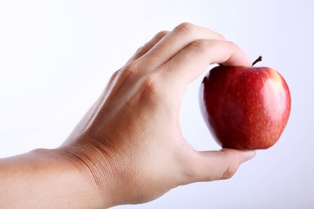 Red apple on hand over white backgroundの写真素材