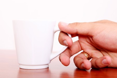 Hand taking white coffee cup. Wooden surfaceの写真素材