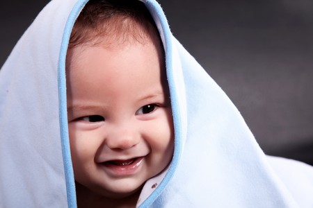 Baby Smiling with blanket on his headの写真素材