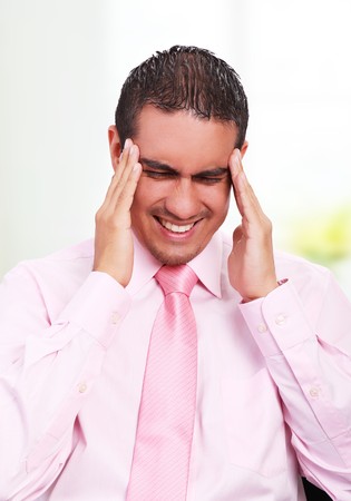 Young businessman with headache, expressing pain with his faceの写真素材