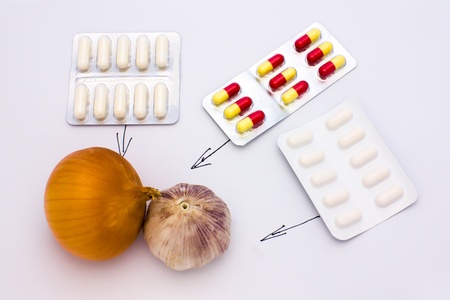 Onions, garlic and medicines on a light backgroundの写真素材