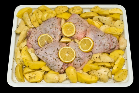 Uncooked chicken thighs with potatoes and lemon.の写真素材