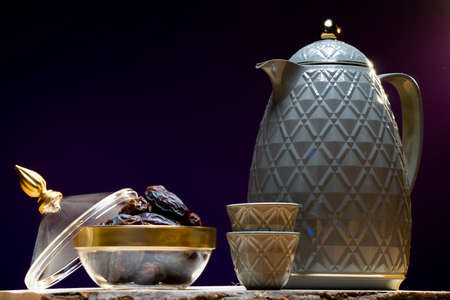 Dried dates and a teapot on a wooden table.の写真素材