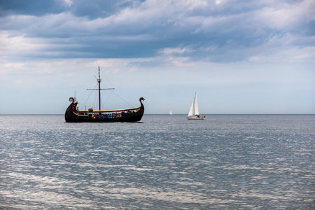 A ship stylized as a Viking boat rides tourists on the Baltic Sea, next to it are two sailing boatsの写真素材