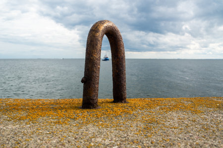 An iron bracket for the installation of a concrete block by a crane against the backdrop of a seascape, located at the entrance to the port.の写真素材